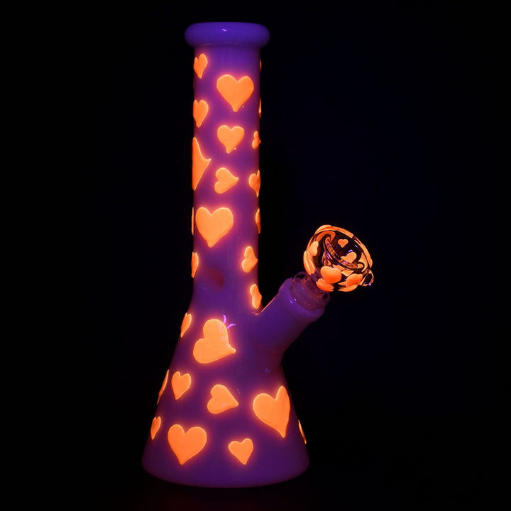 Glow In The Dark Heart Beaker Water Bong glowing brightly in the dark, highlighting luminous accents